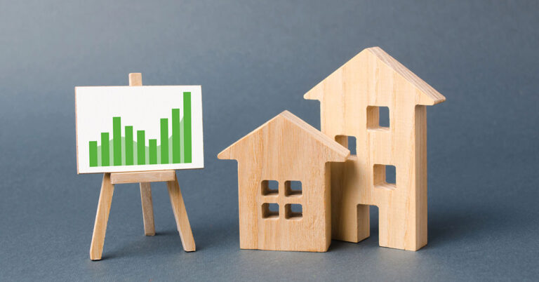 Holzhäuser und eine Lerntafel mit Statistiken als Symbol für die Immobilienwertermittlung