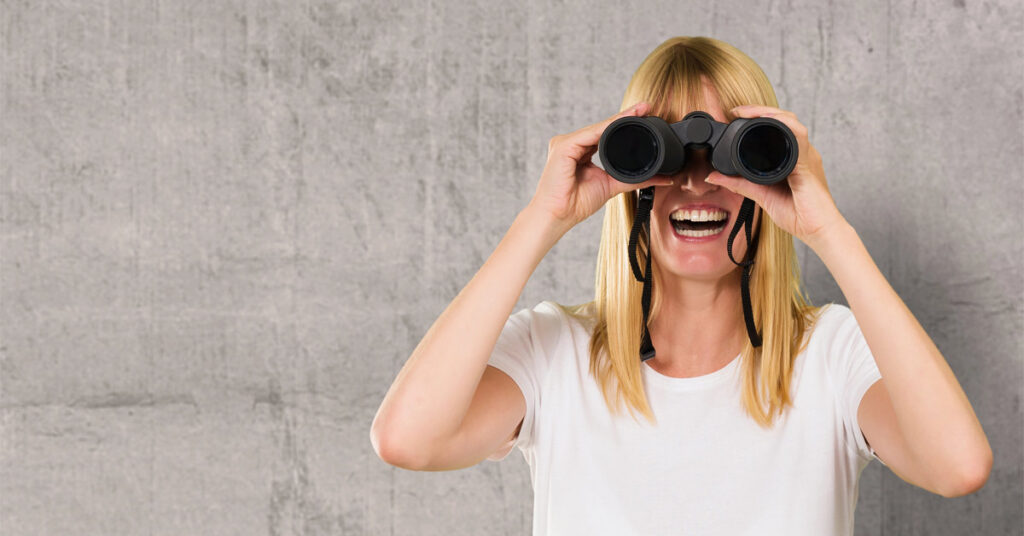 ein frau, die mit einem Fernglas nach einem Käfuer für ihre Immobilie Ausschau hält